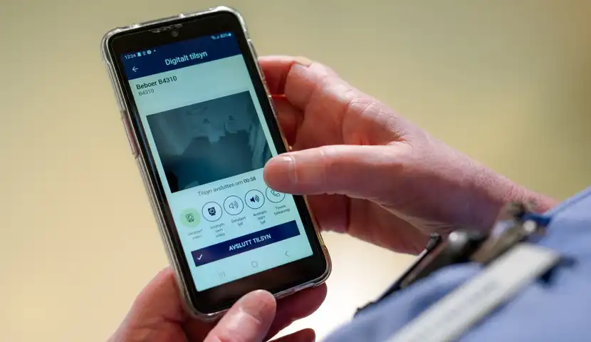 Sykepleier som trykker på mobilen.