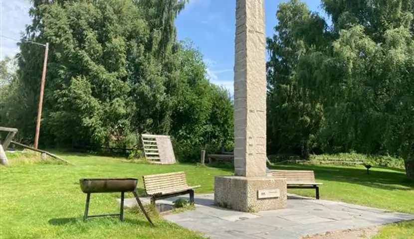 Et monument midt i en park med en grill ved siden av.