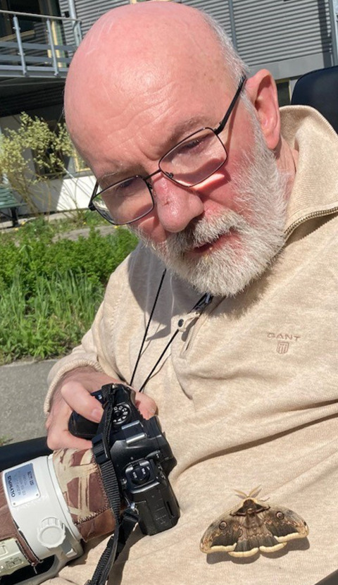 Ole Martin Nilsen sitter med et kamera i hånden og Europas største sommerfugl på magen