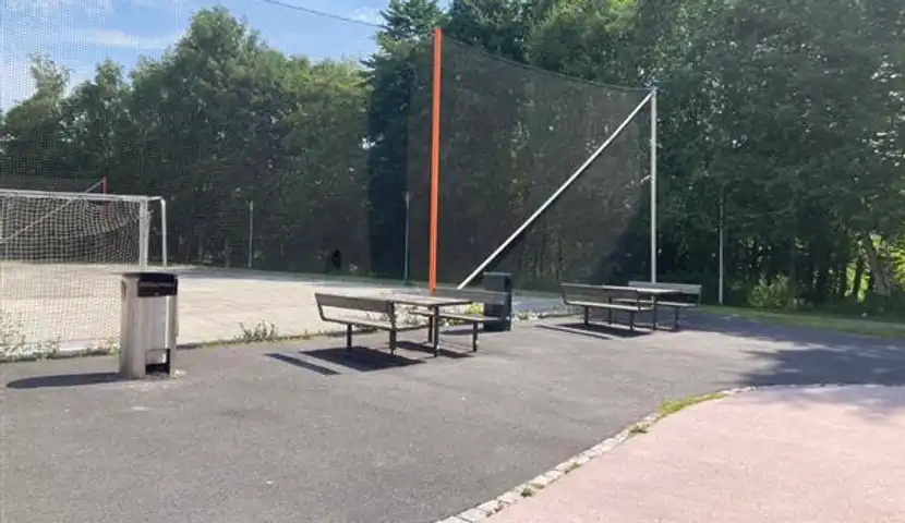 En basketfotballbane med benker og nett og en grill.