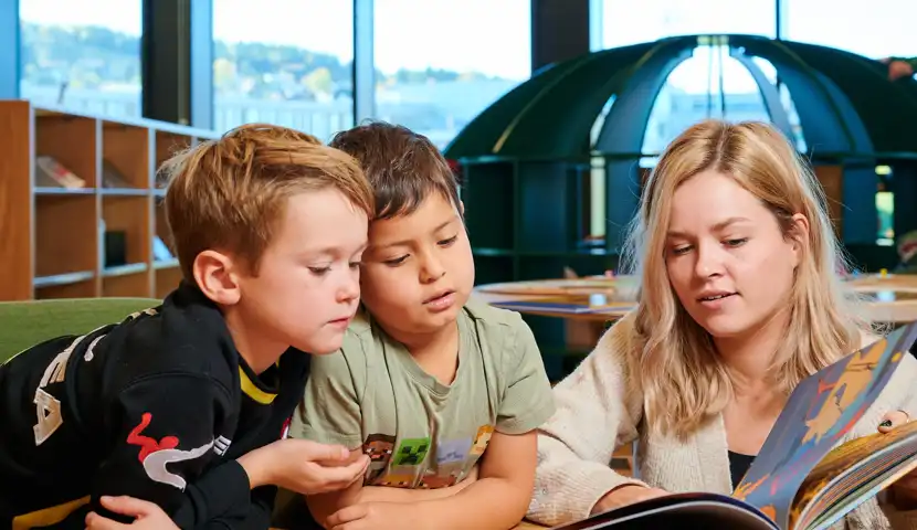 Gutter som leser med bibliotekar på biblioteket