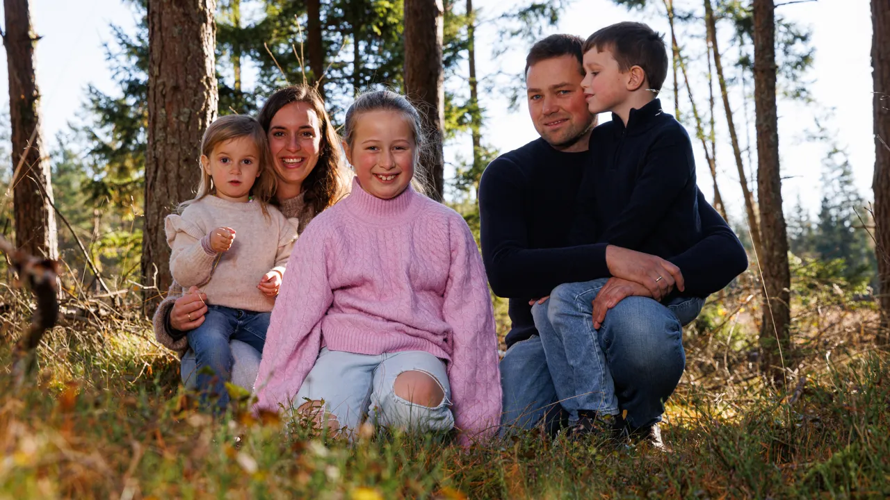 En familie på fem som sitter i skogen.